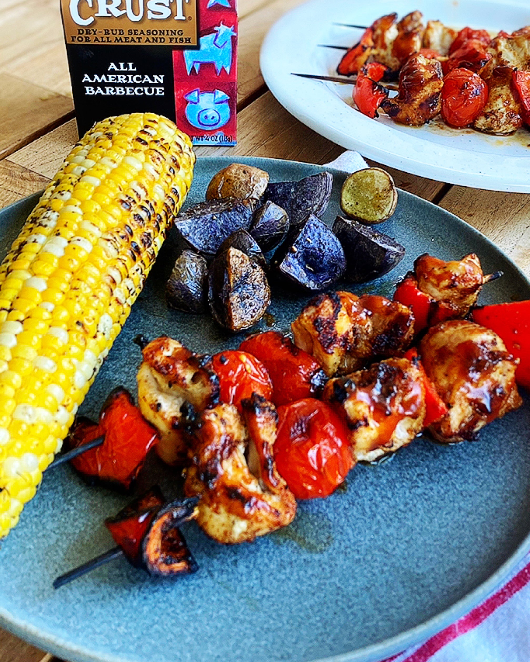 Char Crust® All American Barbecue chicken kabobs on a plate with corn and potatoes on the side.